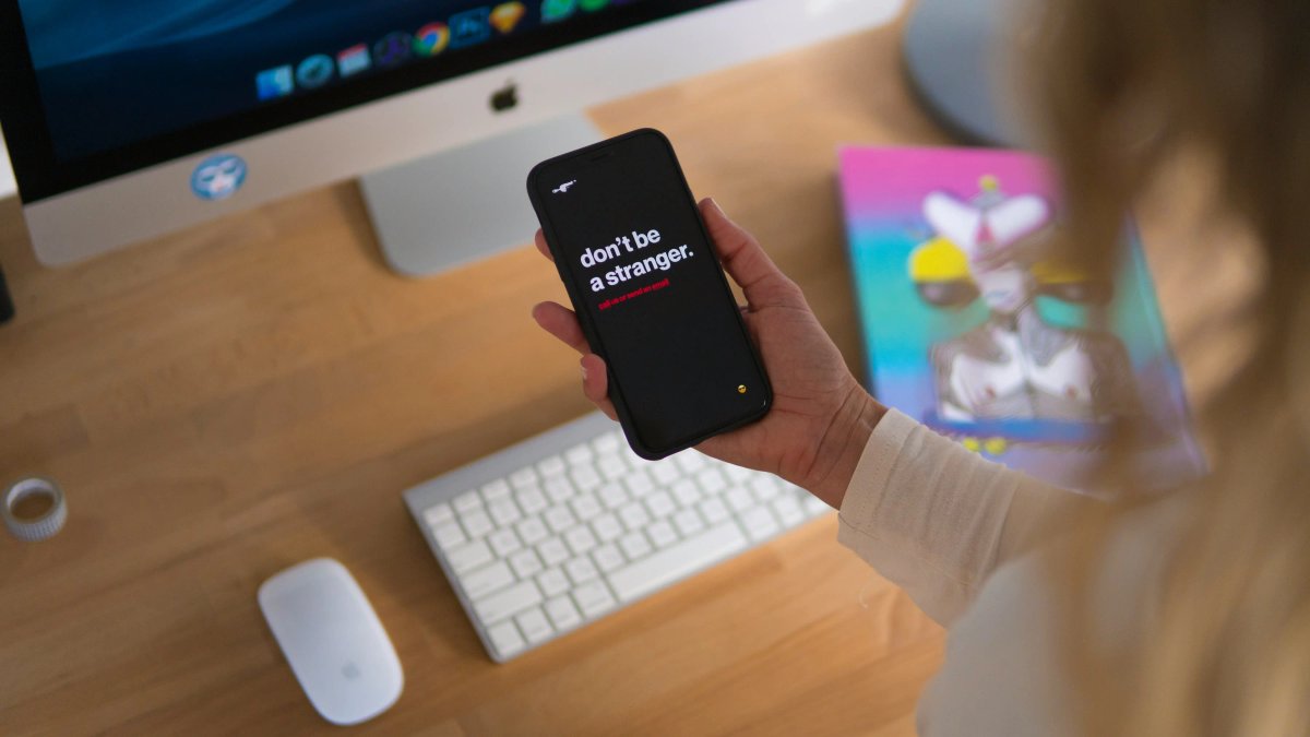 Modern office desk setup with a message 'don't be a stranger' displayed on a phone
